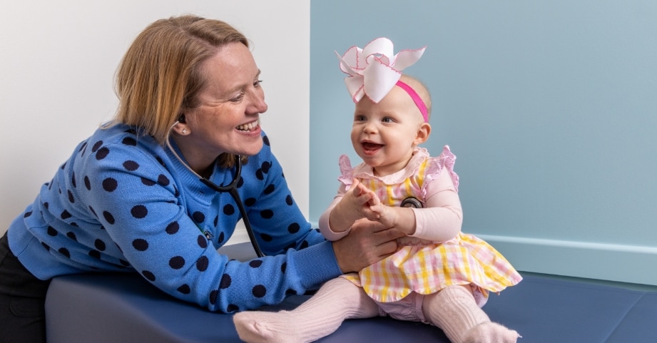 Advanced practice provider checking heart of smiling baby girl