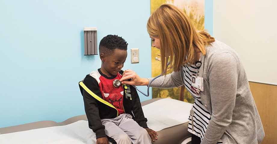 Doctor listening to young boy's heart with stethescope