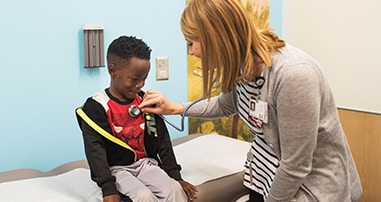 Doctor listening to young boy's heart with stethescope