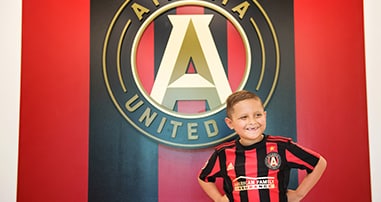 Andrew Jimenez with pediatric cancer smiling in Atlanta United jersey