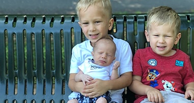 brothers with predisposed genetics for pediatric cancer smiling on park bench