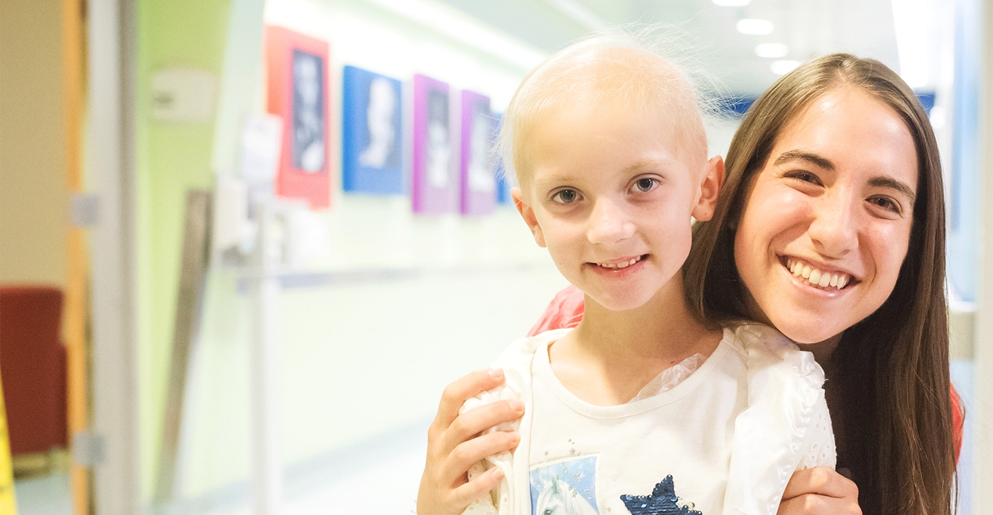 Nurse and young patient girl smile in hallway of pediatric hospital