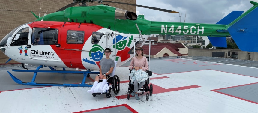 Spine patients in wheel chairs next to helicopter
