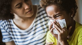 Sick child blowing her nose