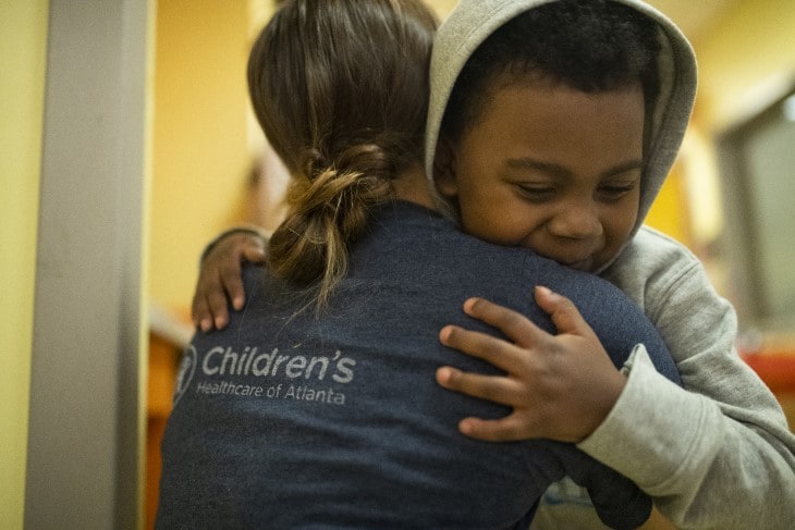 pediatric heart patient boy hugging nurse in hallway at hospital