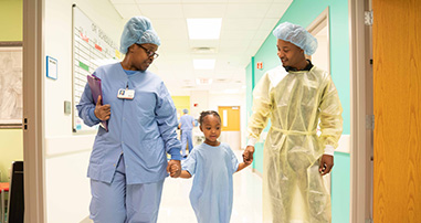 Surgeon, patient and father walk to operating room before surgery.