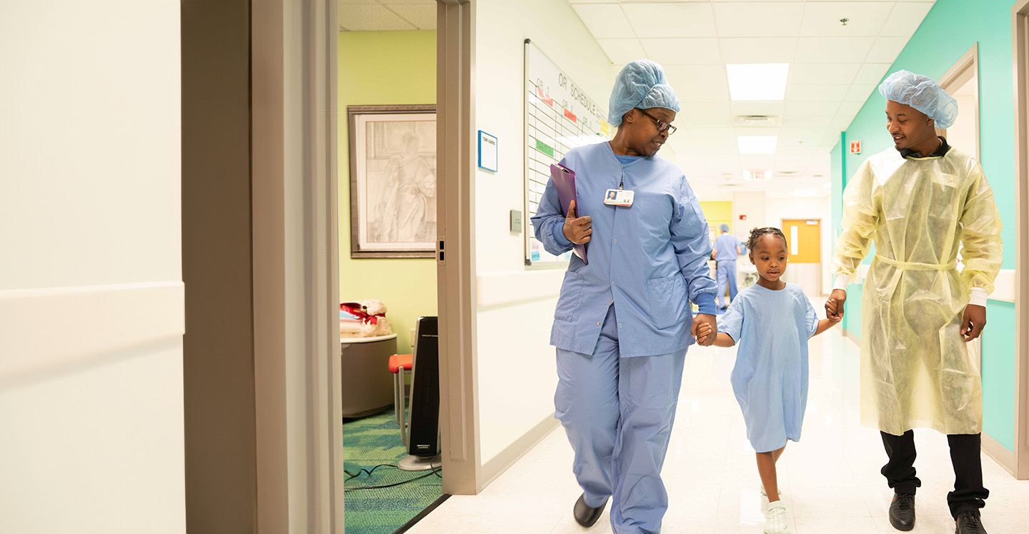 Surgeon, patient and father walk to operating room before surgery.