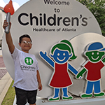 Children's patient smiling in front of sign
