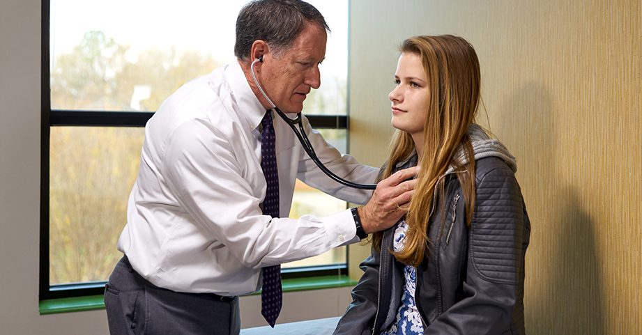 doctor using stethoscope to monitor teen's heart
