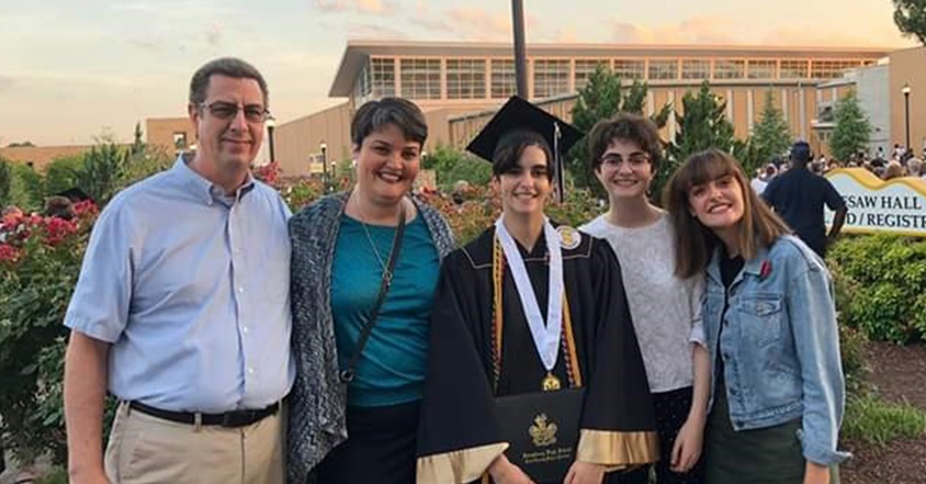 Three teen sisters with scoliosis and spinal bracing pose at family graduation