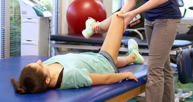 Pediatric physical therapist helping teen patient with hip condition