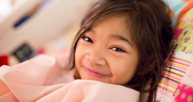 young girl smiling in hospital bed