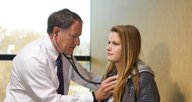 doctor using stethoscope to listen to teen heart