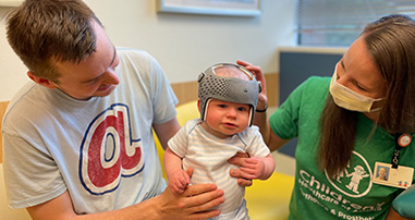 Baby with cranial remolding helmet sees orthotist during a visit.