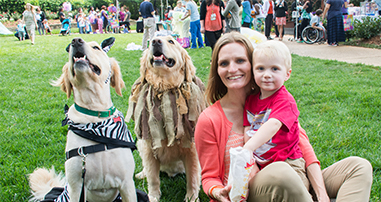 mom smiling with little boy and therapy dogs at pediatric hospital patient family event