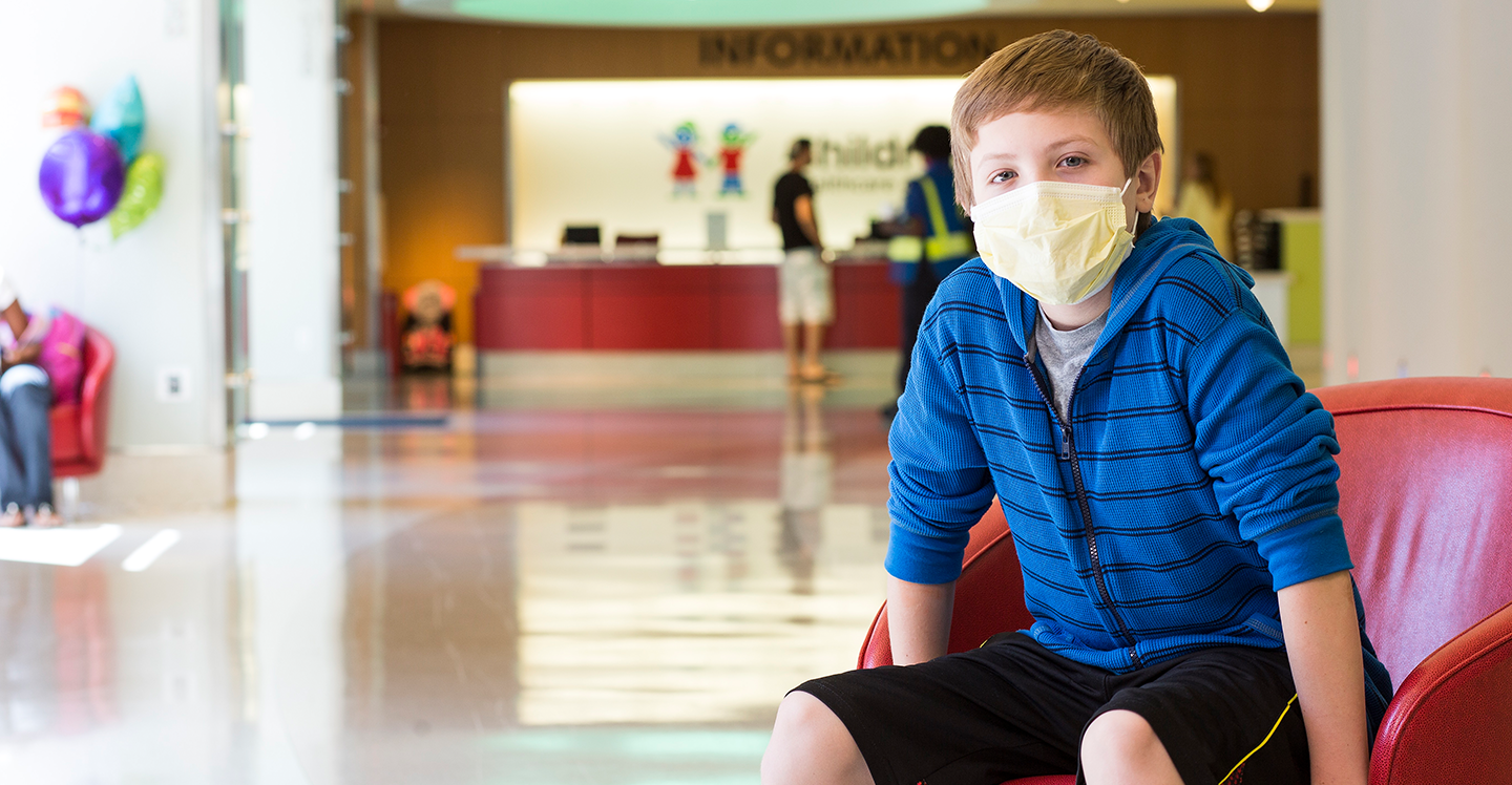 Boy wearing face mask sitting in chair at Egleston hospital