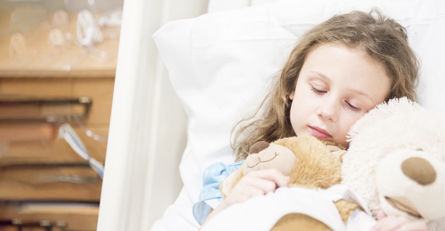 Girl sleeping with stuffed animal in hospital bed