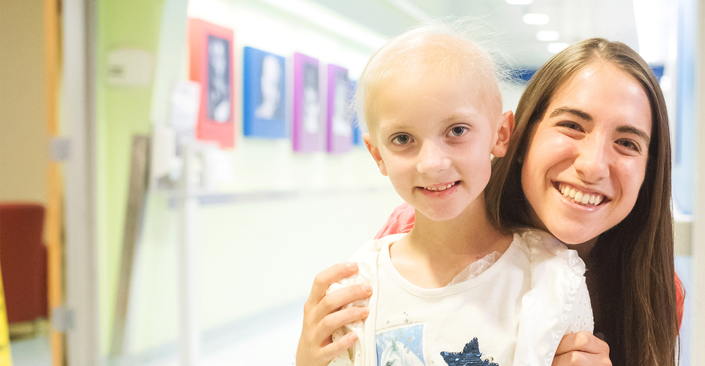 nurse smiles with girl leukemia patient in hospital hallway