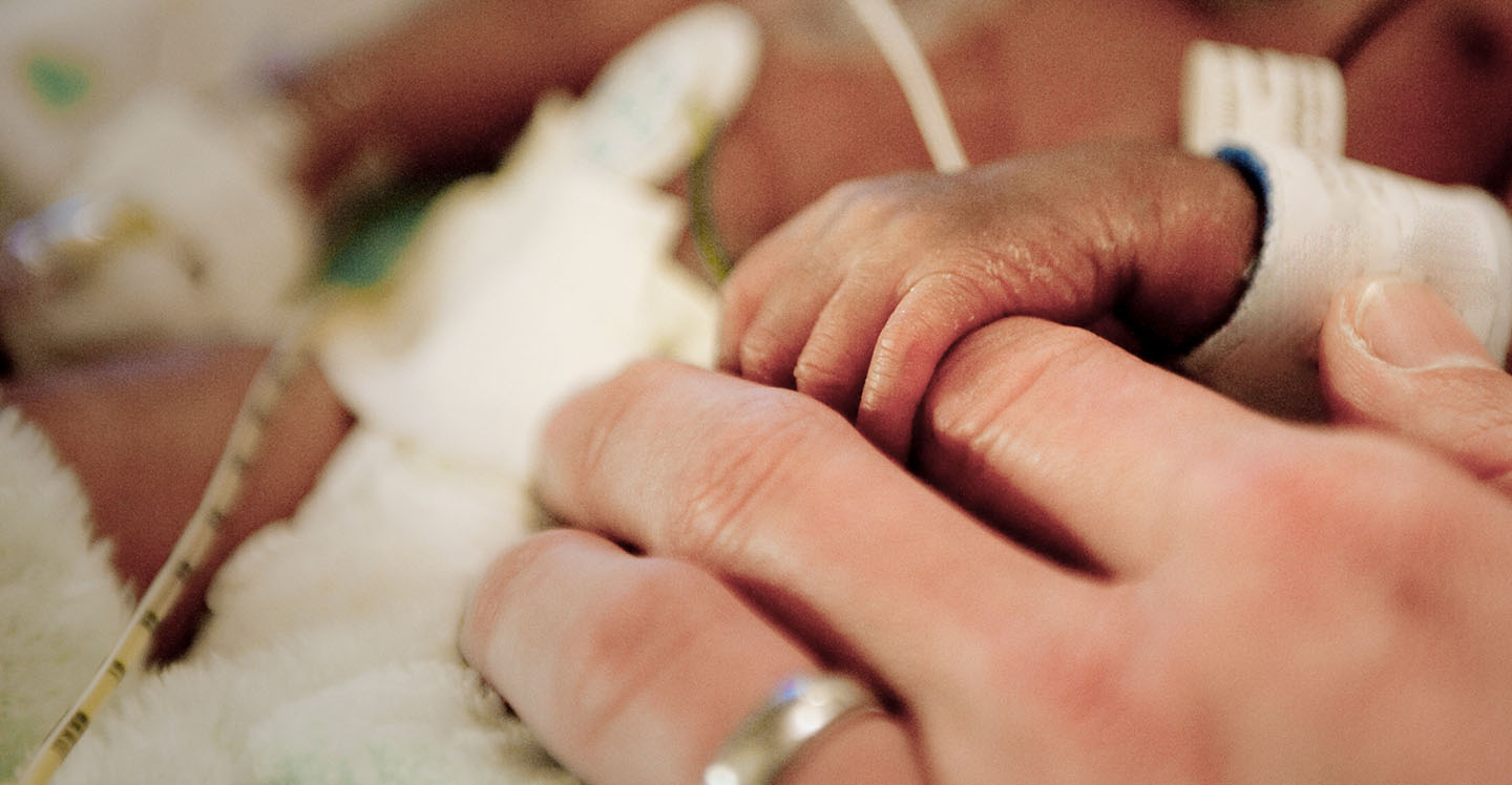 nicu baby holding pediatric nurse's hand