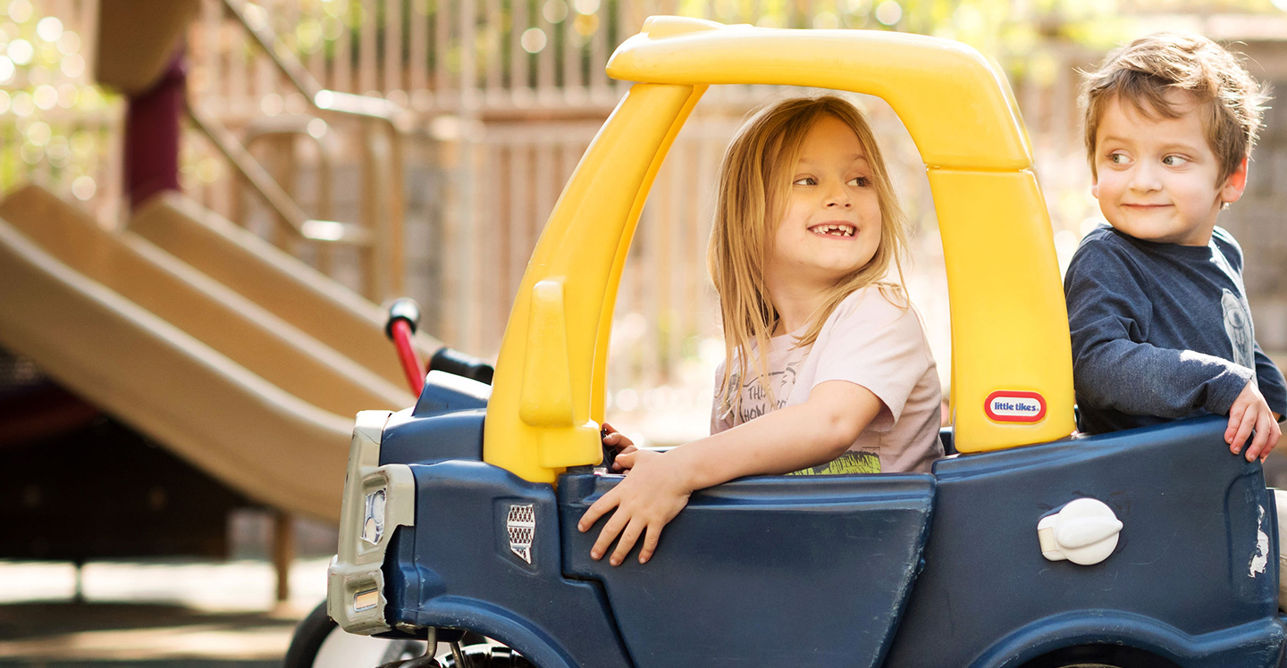 preschoolers ride in car on playground