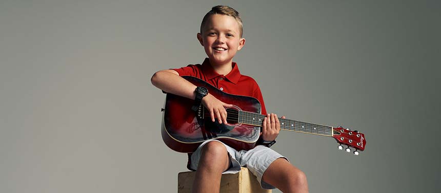 pediatric cancer patient boy smiling with guitar in music therapy