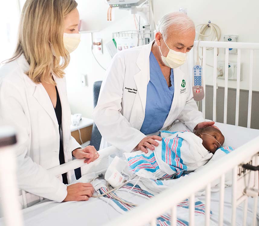 Doctors with baby in crib at pediatric hospital
