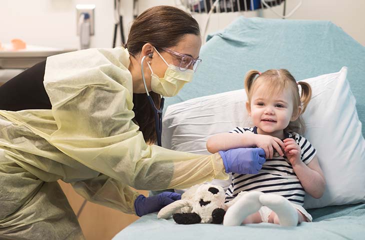 Little girl smiling in hospital bed with nurse