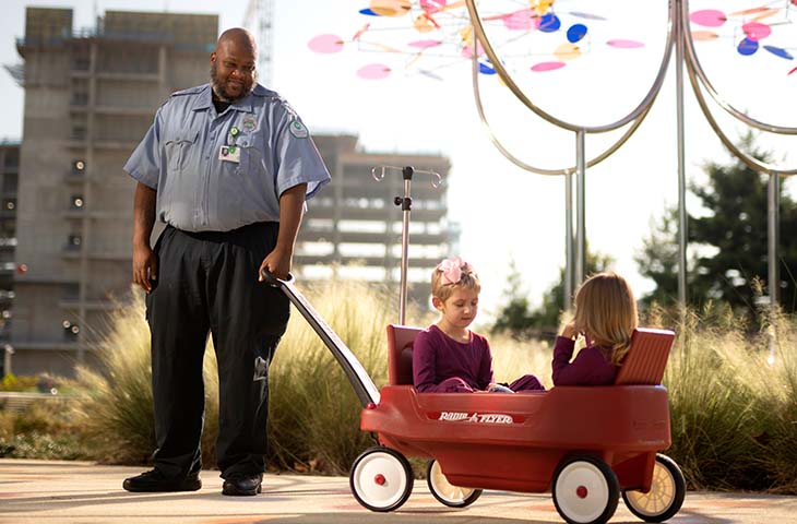 Security guard pulling patients in wagon outside of hospital